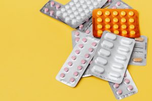A variety of medications laying on a yellow background