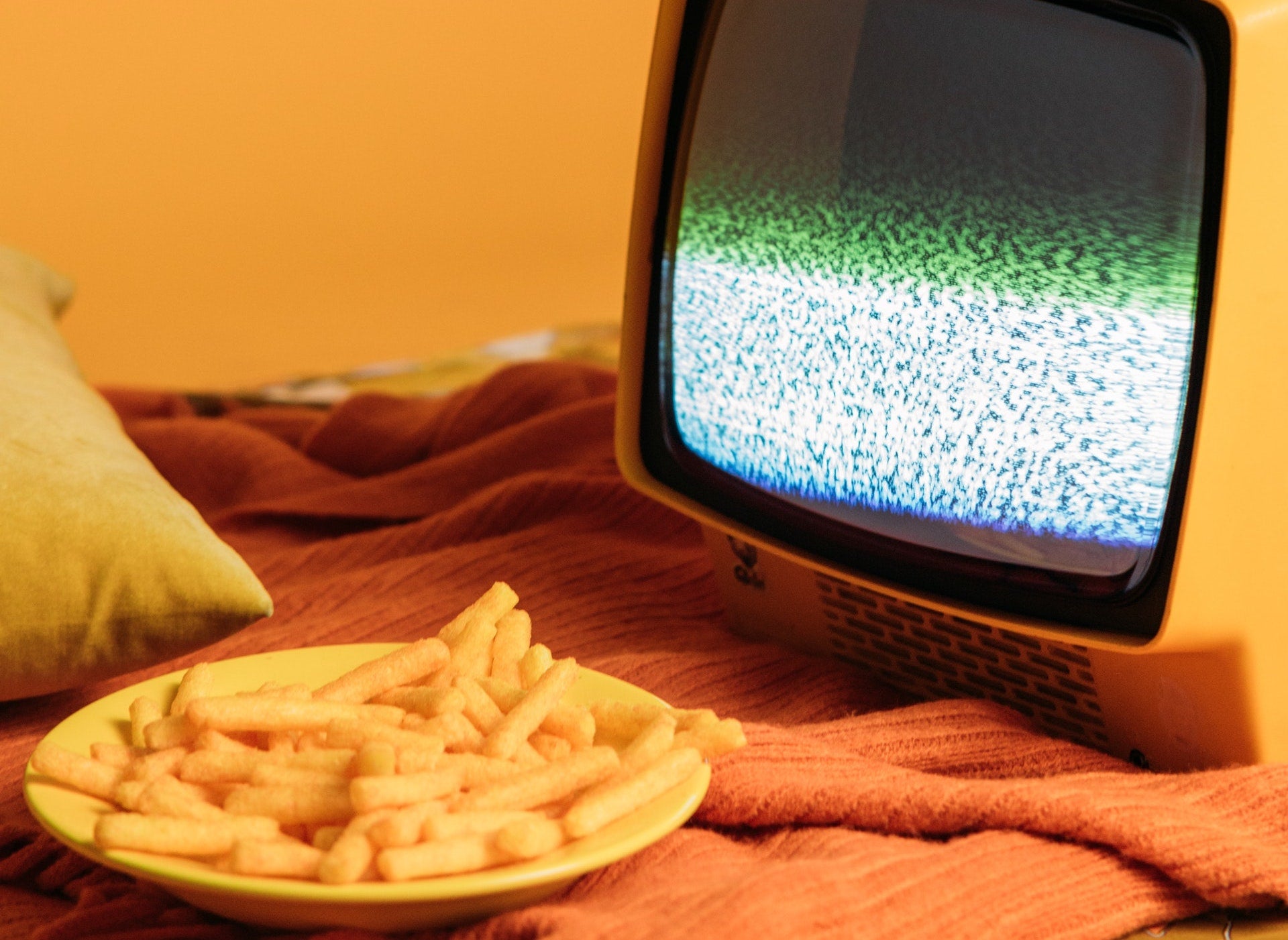 plate of cheese puff snacks next to a television screen to signify advertising junk food