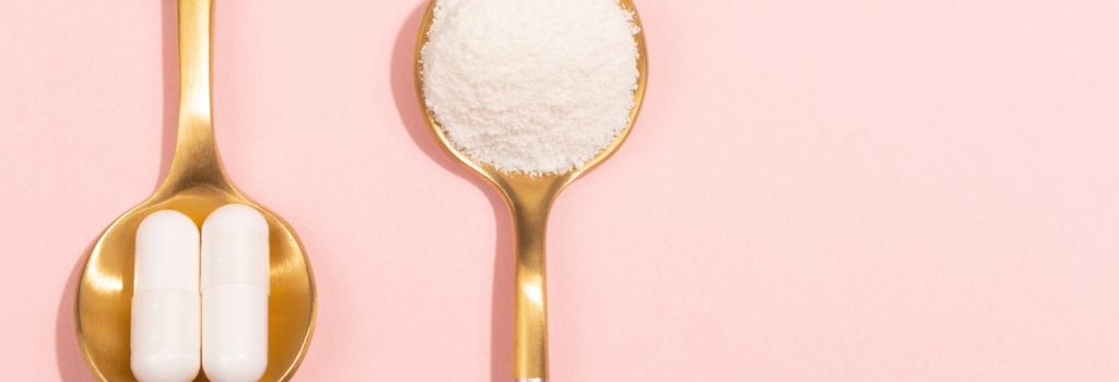 two spoons, one with collagen powder and one with collagen supplements, set on a pink background