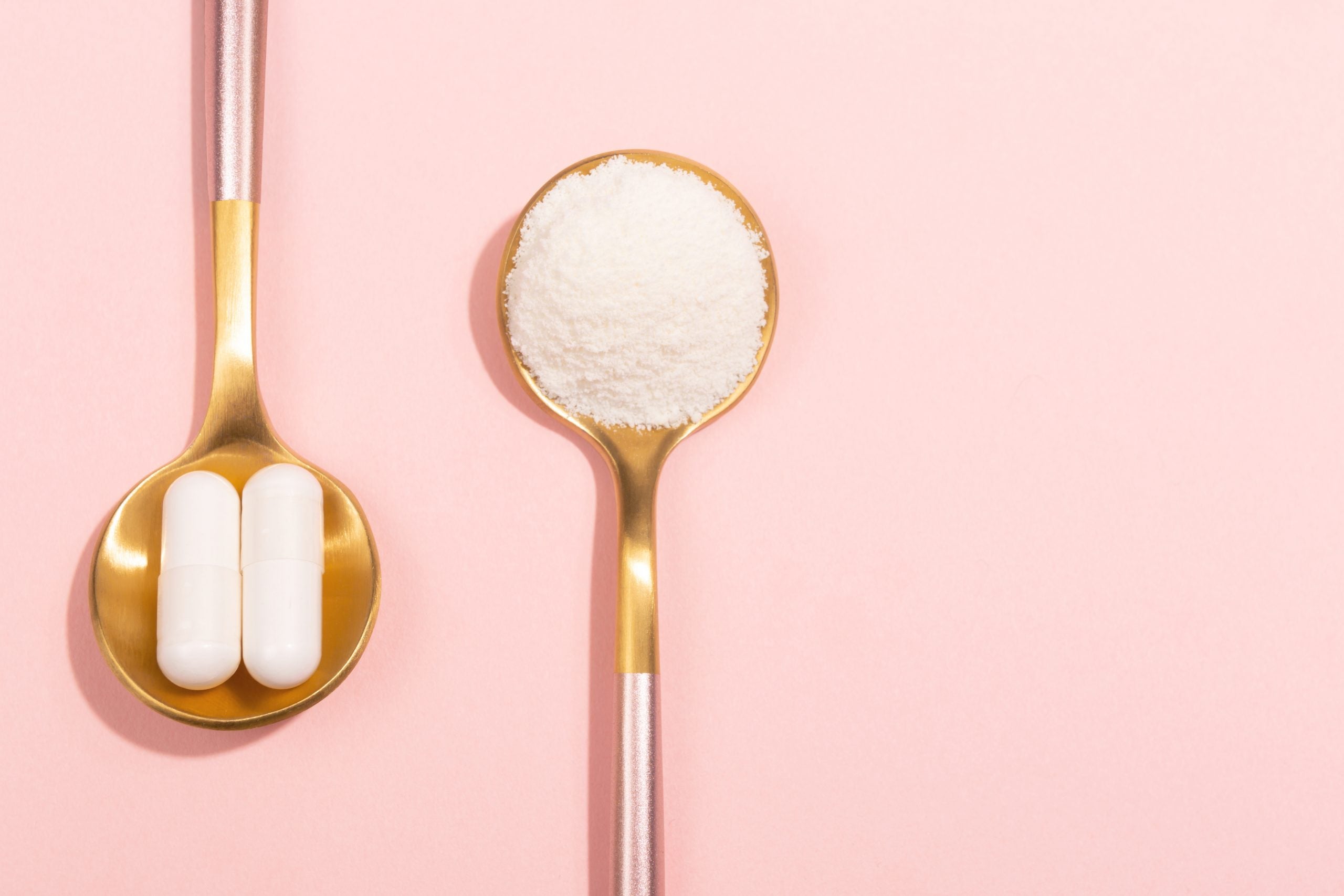 two spoons, one with collagen powder and one with collagen supplements, set on a pink background
