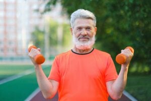 older man exercising with weights outside