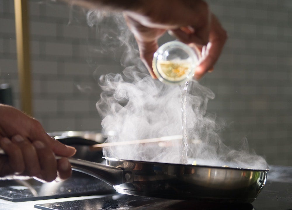 vinegar being poured into a stainless steel pan