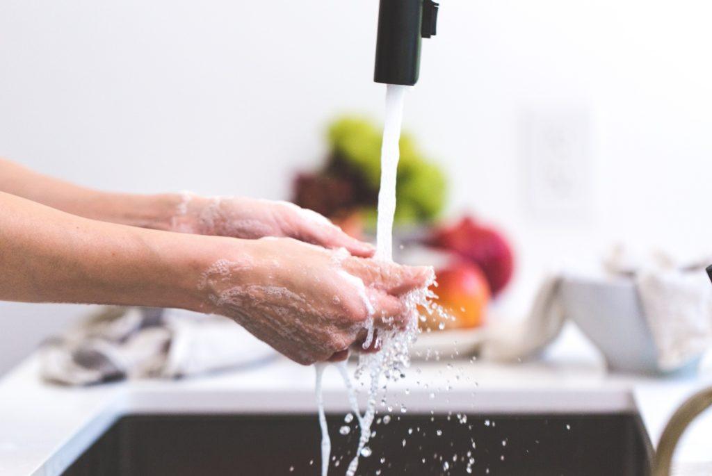 washing hands at a sink with color fruits and vegetables in the counter on the background