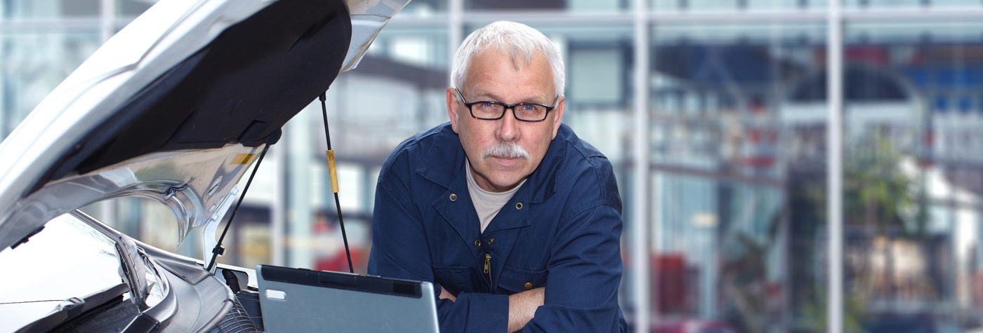 Older man using a computer to service a car