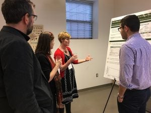 Faculty members discuss a poster