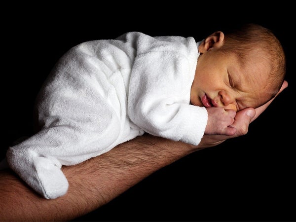 Newborn baby sleeps on the forearm of a man