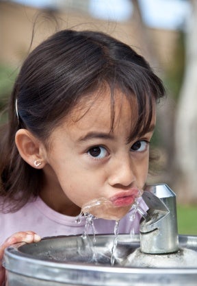 Little girl drinking water from a water fountain