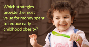 Little girl holding a spoon - The text says: Which strategies provide the most value for money spent to reduce early childhood obesity?