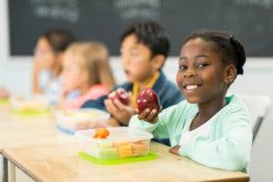 Children in a classroom; little girl eating an apple