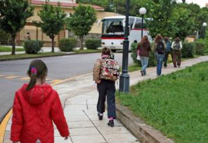 Children walking six feet apart to board the school bus