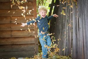 Child jumping in a pile of leaves outside at home