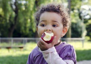 Toddler eating an apple outside