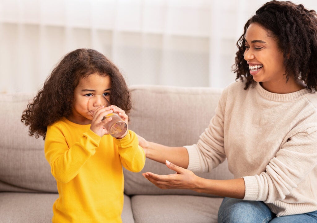 Mom giving glass of water to young daughter