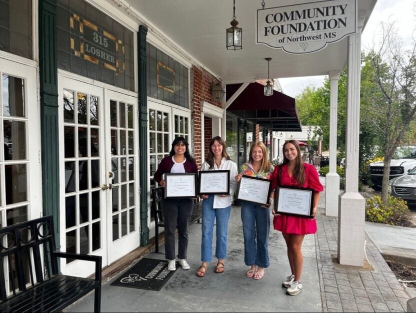 Sophie and 3 other Interns for the Community Foundation of Northwest Mississippi holding up certificates in front of the office