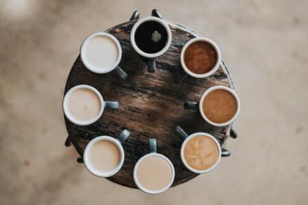 On a circular table, cups of coffee of different shades of colors arranged in a circle.
