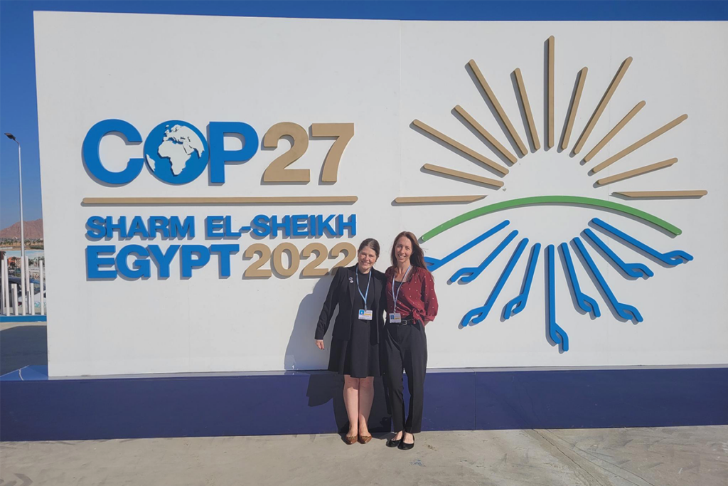 Dr. Kimberly Humphrey and Dr. Tess Wiskel standing in front of the COP27 conference logo.
