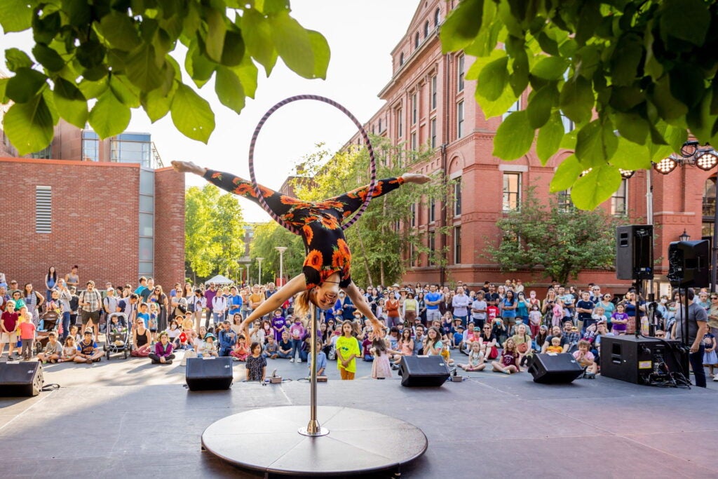 Circus performer doing a handstand with a hoop in front of a large audience. Photo by Caitlin Cunningham Photography LLC.