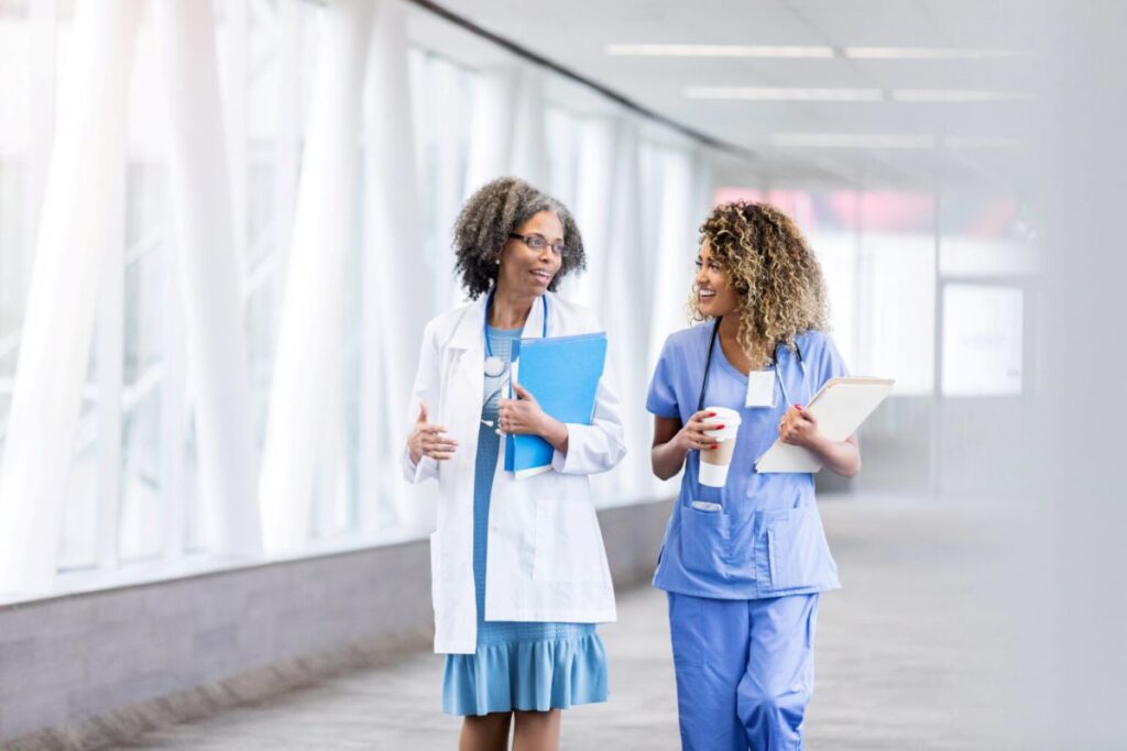 Two female health care workers walking down a hall talking