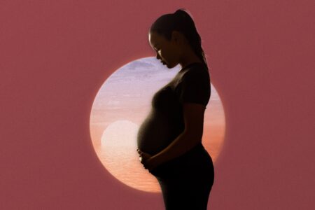 Profile of a pregnant woman holding her belly with sky background