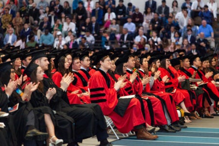 Graduating students sit at the Reggie Lewis Center in academic regalia at the 2023 ceremony