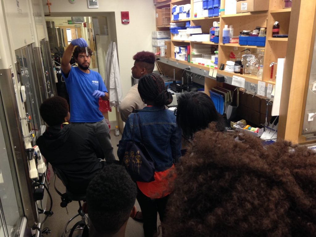 Research assistant Matthew Lopes explains to Shaneice Browh and other visiting Codman Academy students how he measures the fat content in blood samples.