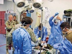 Public health strategies such as reducing lag time between injury and surgery have saved lives in the Afghanistan war. Michael McCarten, MPH ’99 (left) watches as a medical team resuscitates an Afghan child in an emergency room at the Role III trauma center in Kandahar.