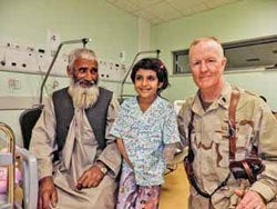 Michael McCarten with an Afghan girl and her father. The girl lost her lower left arm in a bus accident and suffered other serious injuries. McCarten’s team performed several surgeries to ensure her survival.