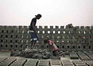In the Indian state of West Bengal, a young man and a girl make clay for a brick kiln. Brickmaking is common employment for bonded laborers.