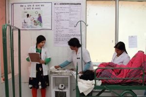 Birth attendants and a BetterBirth coach use the Safe Childbirth Checklist, hanging on the wall, at a facility in Uttar Pradesh to ensure quality care for the new mother and baby.