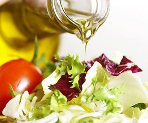 Olive oil being poured onto salad with tomatoes