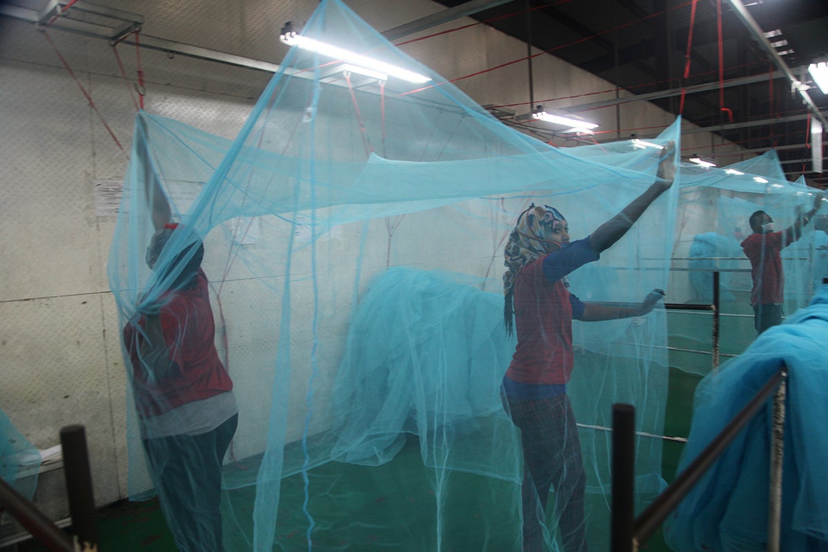 Workers examine insecticide-treated mosquito bed nets in Tanzania